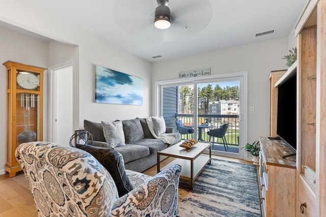 living room with a ceiling fan, light wood finished floors, and visible vents