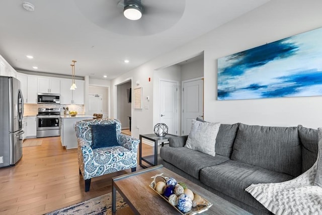 living room featuring recessed lighting, a ceiling fan, and light wood-style flooring