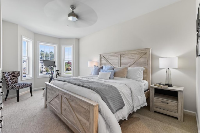 bedroom with a ceiling fan, baseboards, and light colored carpet