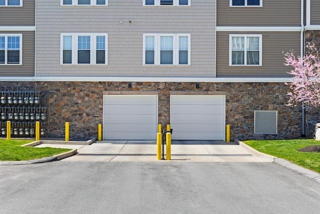 exterior space featuring a garage, stone siding, and concrete driveway