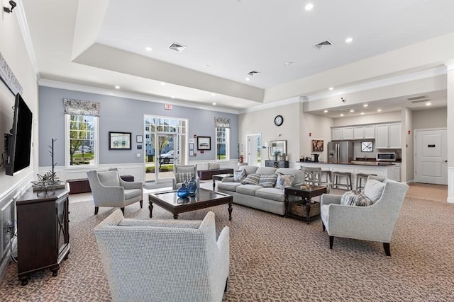 living area featuring recessed lighting, light colored carpet, wainscoting, and a raised ceiling