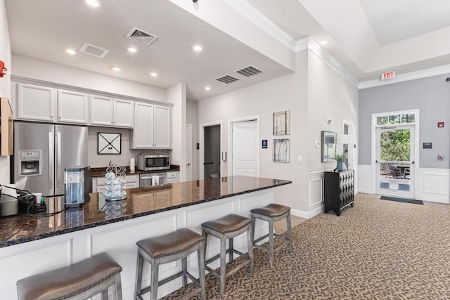 kitchen with recessed lighting, dark stone counters, stainless steel appliances, and a kitchen bar