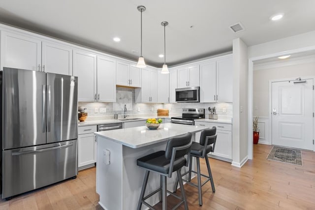 kitchen with a sink, appliances with stainless steel finishes, white cabinets, and light countertops