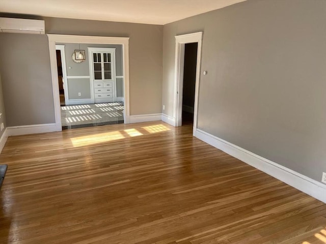 135-137 Summer St, Waltham, MA 02452 - spare room featuring an AC wall unit, wood finished floors, and baseboards