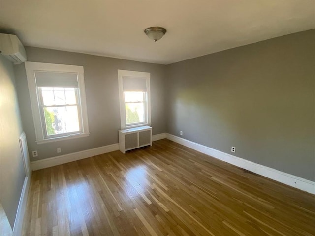 135-137 Summer St, Waltham, MA 02452 - empty room featuring radiator heating unit, a wall unit AC, plenty of natural light, and wood finished floors