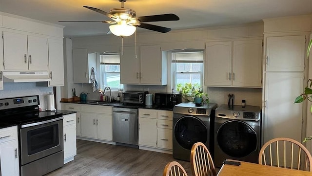 135-137 Summer St, Waltham, MA 02452 - kitchen featuring stainless steel appliances, under cabinet range hood, a sink, washer and clothes dryer, and dark countertops