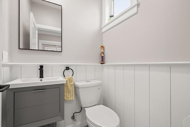 bathroom featuring toilet, a wainscoted wall, and vanity