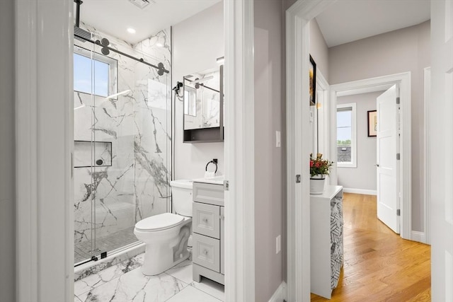 bathroom featuring a marble finish shower, toilet, vanity, and baseboards
