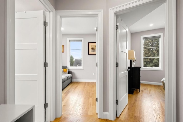 corridor featuring baseboards and light wood-style flooring