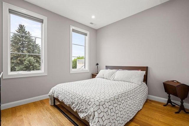 bedroom with baseboards, multiple windows, light wood-style flooring, and recessed lighting