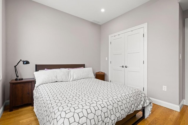 bedroom featuring light wood-style flooring, baseboards, a closet, and recessed lighting