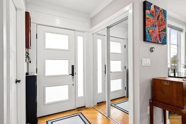 entrance foyer featuring crown molding, light wood-style floors, and healthy amount of natural light