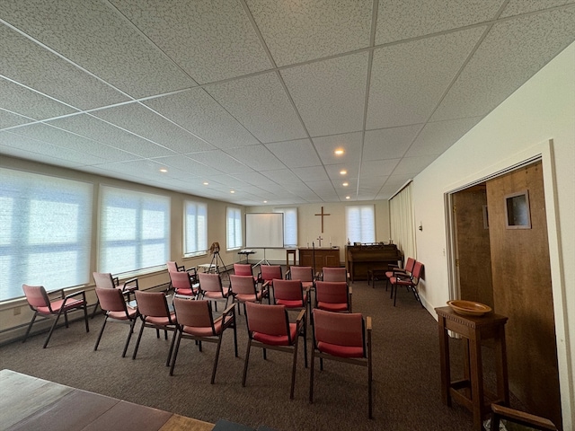 carpeted dining space with plenty of natural light and a drop ceiling