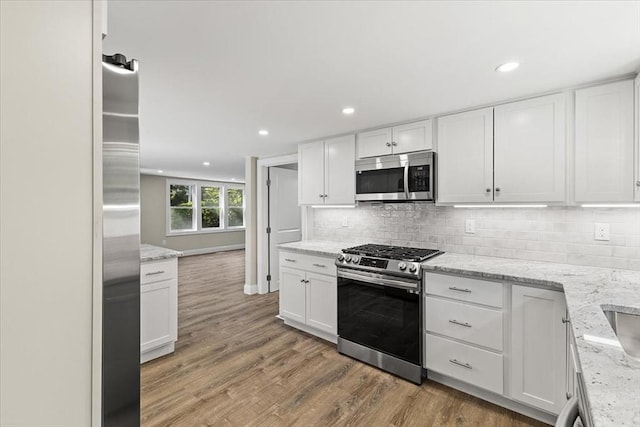 kitchen with light wood-type flooring, stainless steel appliances, and white cabinetry