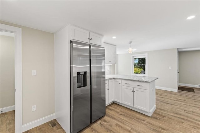 kitchen with light stone countertops, white cabinets, stainless steel refrigerator with ice dispenser, light hardwood / wood-style floors, and kitchen peninsula