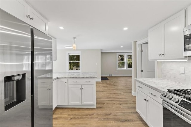 kitchen with appliances with stainless steel finishes, light stone counters, and white cabinetry