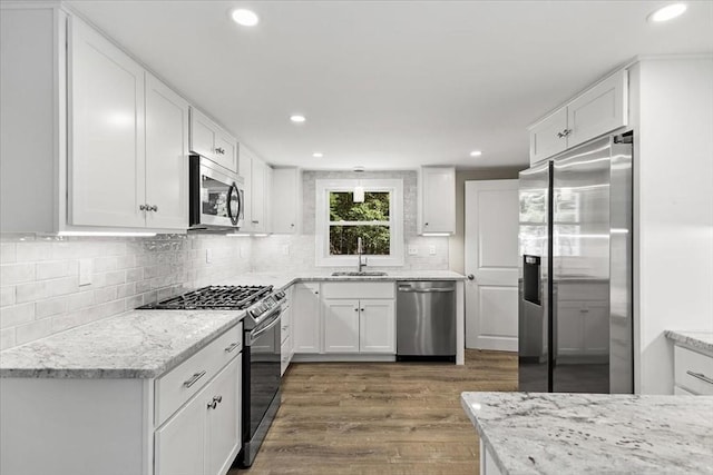 kitchen featuring sink, light stone countertops, dark wood-type flooring, stainless steel appliances, and white cabinets