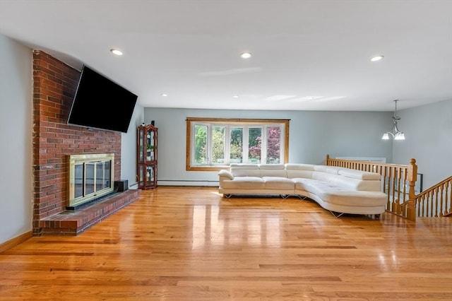 living room with light wood-style flooring, a baseboard heating unit, a fireplace, recessed lighting, and baseboards