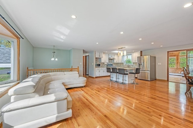 living area with plenty of natural light, light wood-style floors, recessed lighting, and a chandelier