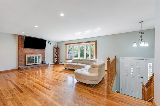 living room with light wood-style floors, a chandelier, recessed lighting, a baseboard heating unit, and baseboards