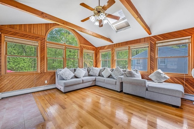 living area featuring wooden walls, baseboard heating, light wood-type flooring, and a ceiling fan