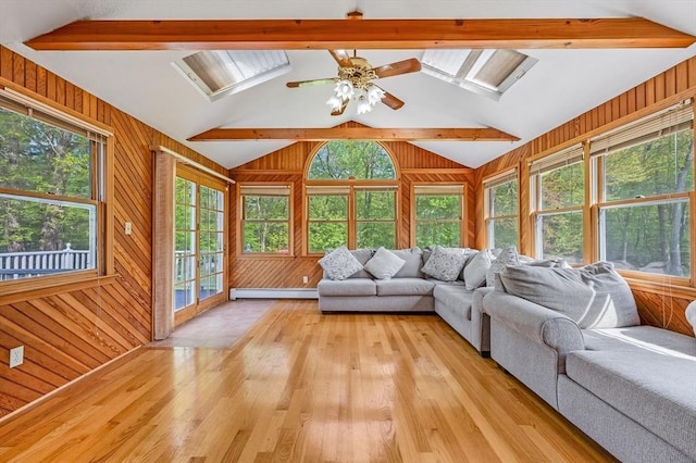 living room with plenty of natural light, wood walls, light wood-style floors, and a skylight