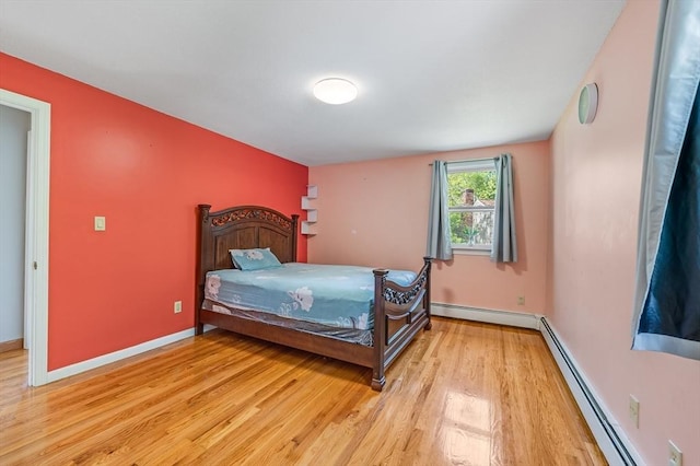bedroom with light wood finished floors, a baseboard radiator, baseboards, and a baseboard heating unit