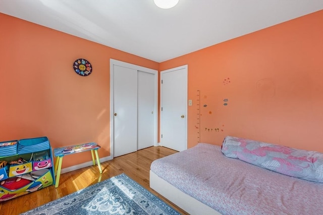 bedroom with wood finished floors, a closet, and baseboards