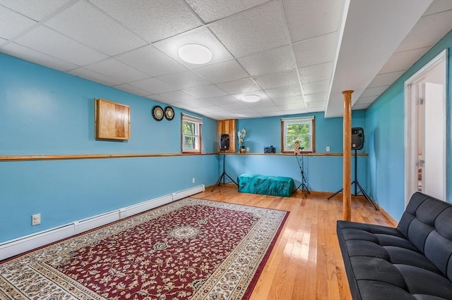 sitting room featuring baseboard heating, a paneled ceiling, and hardwood / wood-style flooring