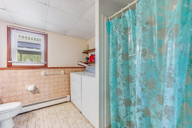 bathroom featuring baseboard heating, separate washer and dryer, tile walls, a paneled ceiling, and toilet