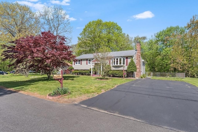 bi-level home with a chimney and asphalt driveway