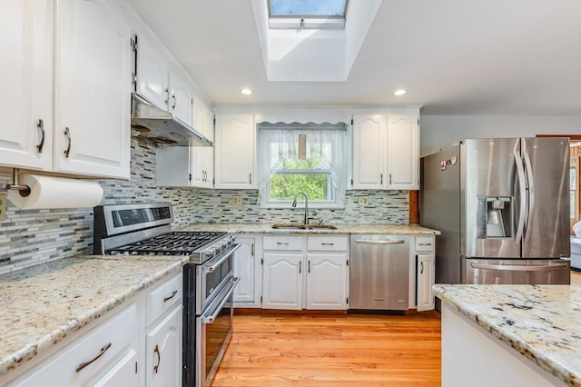kitchen featuring stainless steel appliances, under cabinet range hood, a sink, white cabinets, and recessed lighting