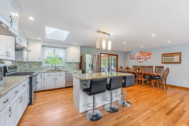 kitchen with stainless steel appliances, a skylight, plenty of natural light, a kitchen bar, and recessed lighting