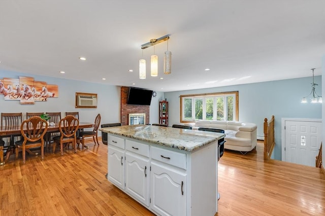 kitchen with open floor plan, light wood finished floors, white cabinetry, pendant lighting, and recessed lighting