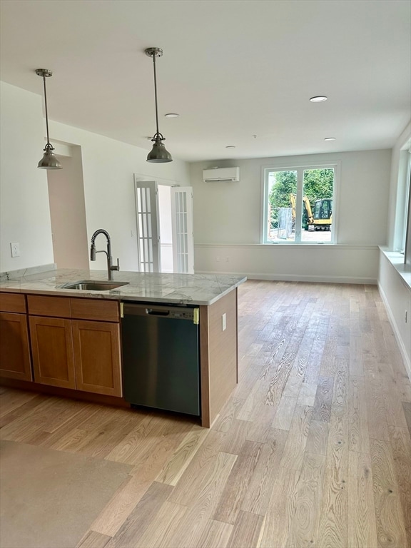 kitchen featuring sink, light hardwood / wood-style flooring, decorative light fixtures, and stainless steel dishwasher