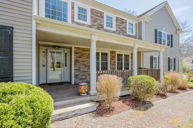 doorway to property with covered porch and stone siding