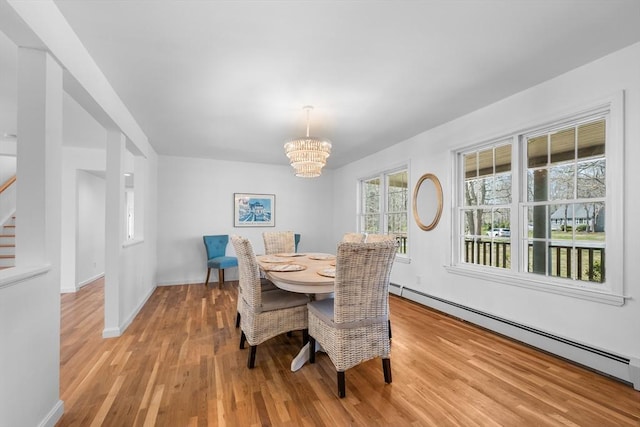 dining space with a baseboard radiator, a chandelier, stairs, light wood-style flooring, and baseboards