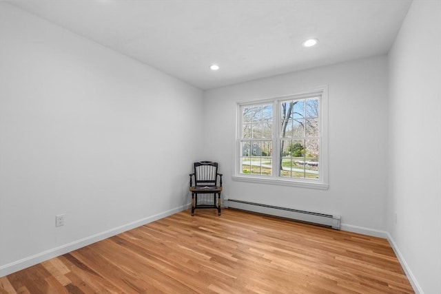 unfurnished room featuring a baseboard heating unit, light wood finished floors, baseboards, and recessed lighting