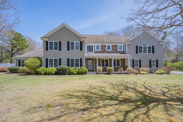 view of front of house featuring a porch, a front lawn, and stone siding