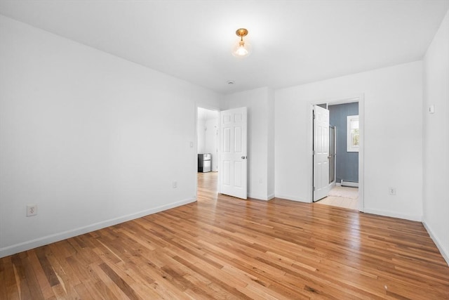 spare room featuring light wood-type flooring, baseboards, and baseboard heating