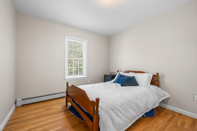 bedroom featuring baseboard heating, wood finished floors, and baseboards