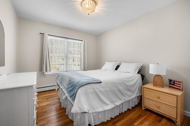 bedroom featuring a baseboard heating unit and wood finished floors