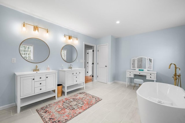 full bath featuring two vanities, a freestanding bath, baseboards, and recessed lighting