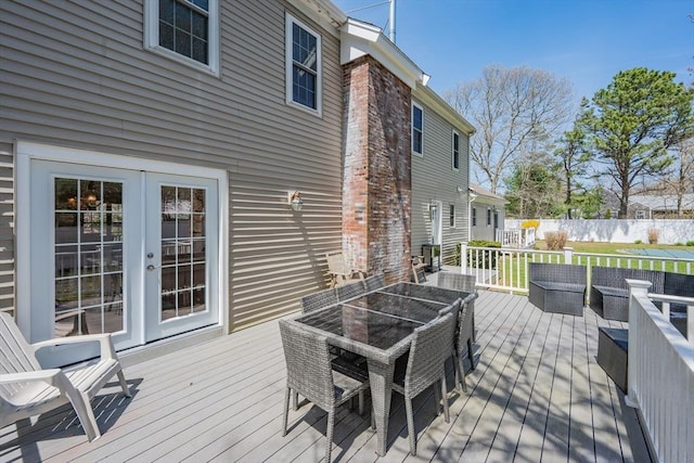 wooden terrace featuring outdoor dining space, outdoor lounge area, french doors, and fence