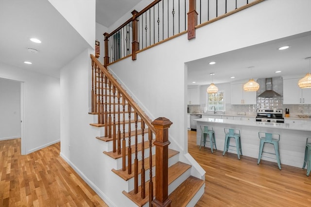 stairs with wood finished floors, recessed lighting, and baseboards