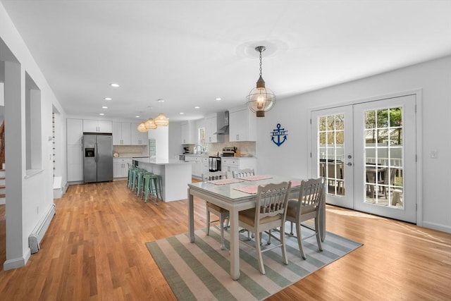 dining room with a baseboard heating unit, french doors, light wood-type flooring, recessed lighting, and stairs