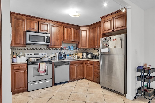 kitchen featuring decorative backsplash, sink, light tile patterned flooring, and appliances with stainless steel finishes