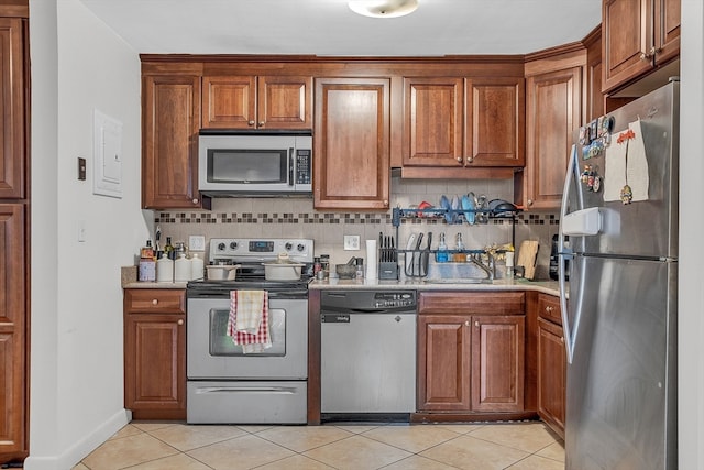 kitchen with light tile patterned flooring, backsplash, stainless steel appliances, and sink