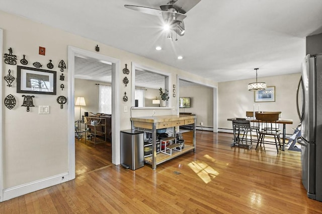 interior space featuring stainless steel refrigerator, ceiling fan, hardwood / wood-style floors, and pendant lighting