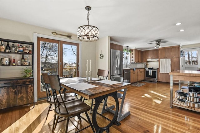 dining area featuring sink, ceiling fan with notable chandelier, and light wood-type flooring